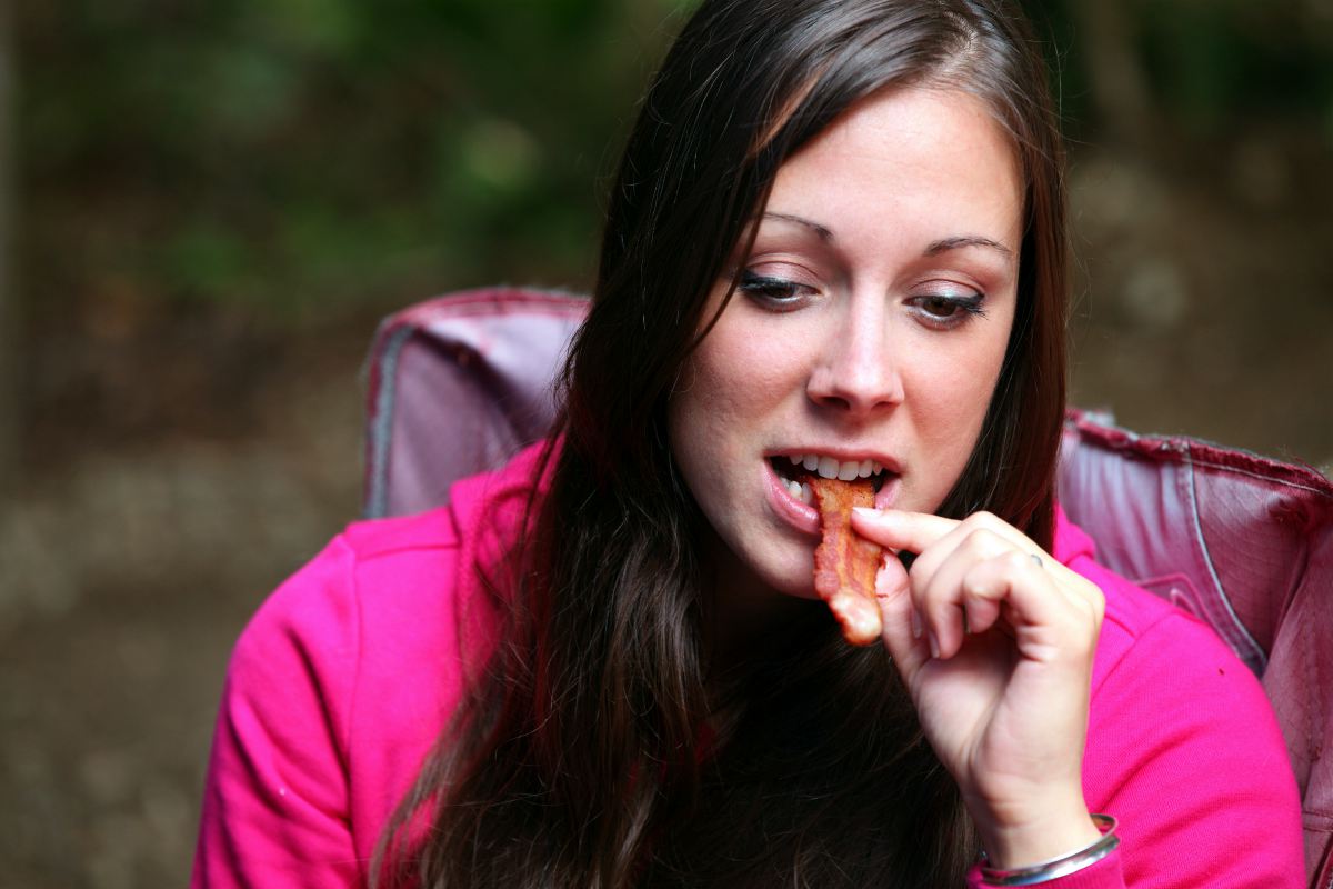 Người phụ nữ trẻ đẹp thưởng thức một lát thịt xông khói | 7 lầm tưởng và lời nói dối phổ biến về Keto